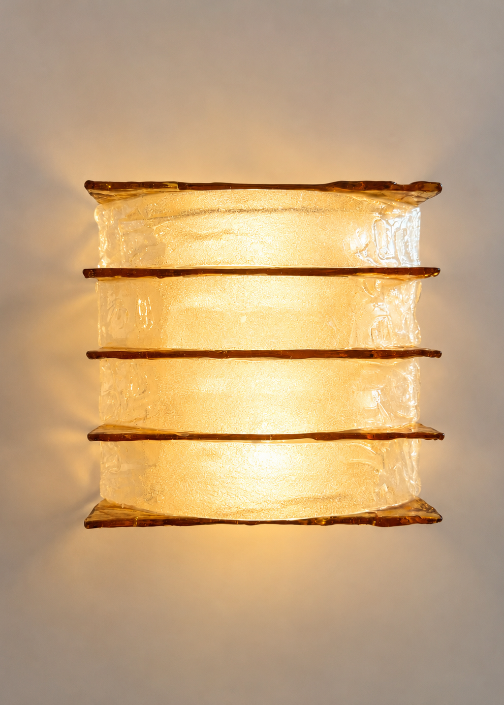A vintage-style rectangular wall sconce featuring four stacked tiers of textured, crackled clear glass with warm amber-brown metallic trim, shown against a plain light gray background.