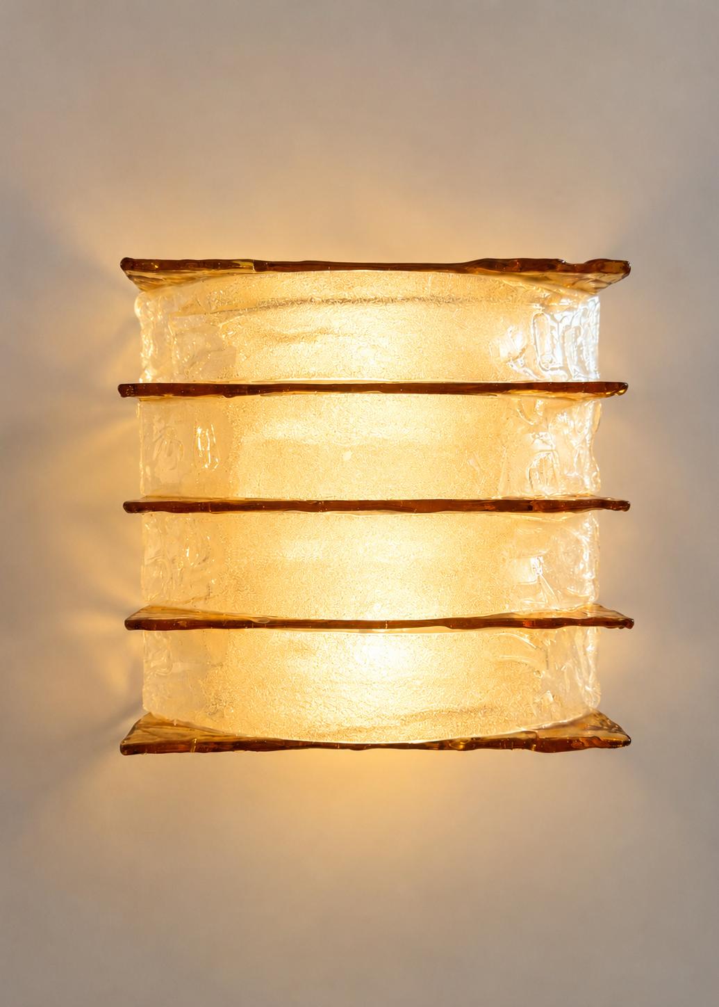 A vintage-style rectangular wall sconce featuring four stacked tiers of textured, crackled clear glass with warm amber-brown metallic trim, shown against a plain light gray background.