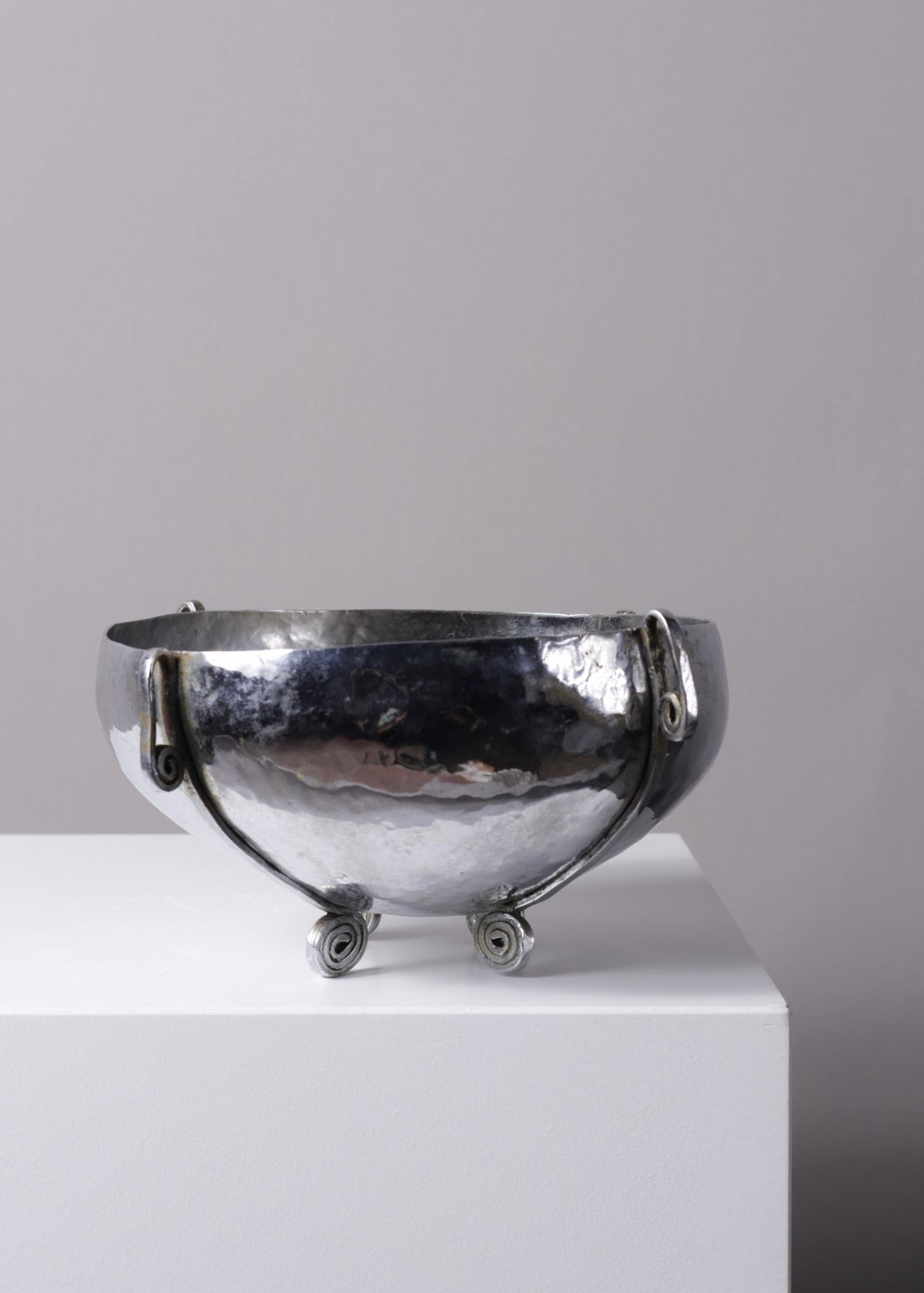 Detail of the raised foot and curved profile of the English silver-plated bowl.