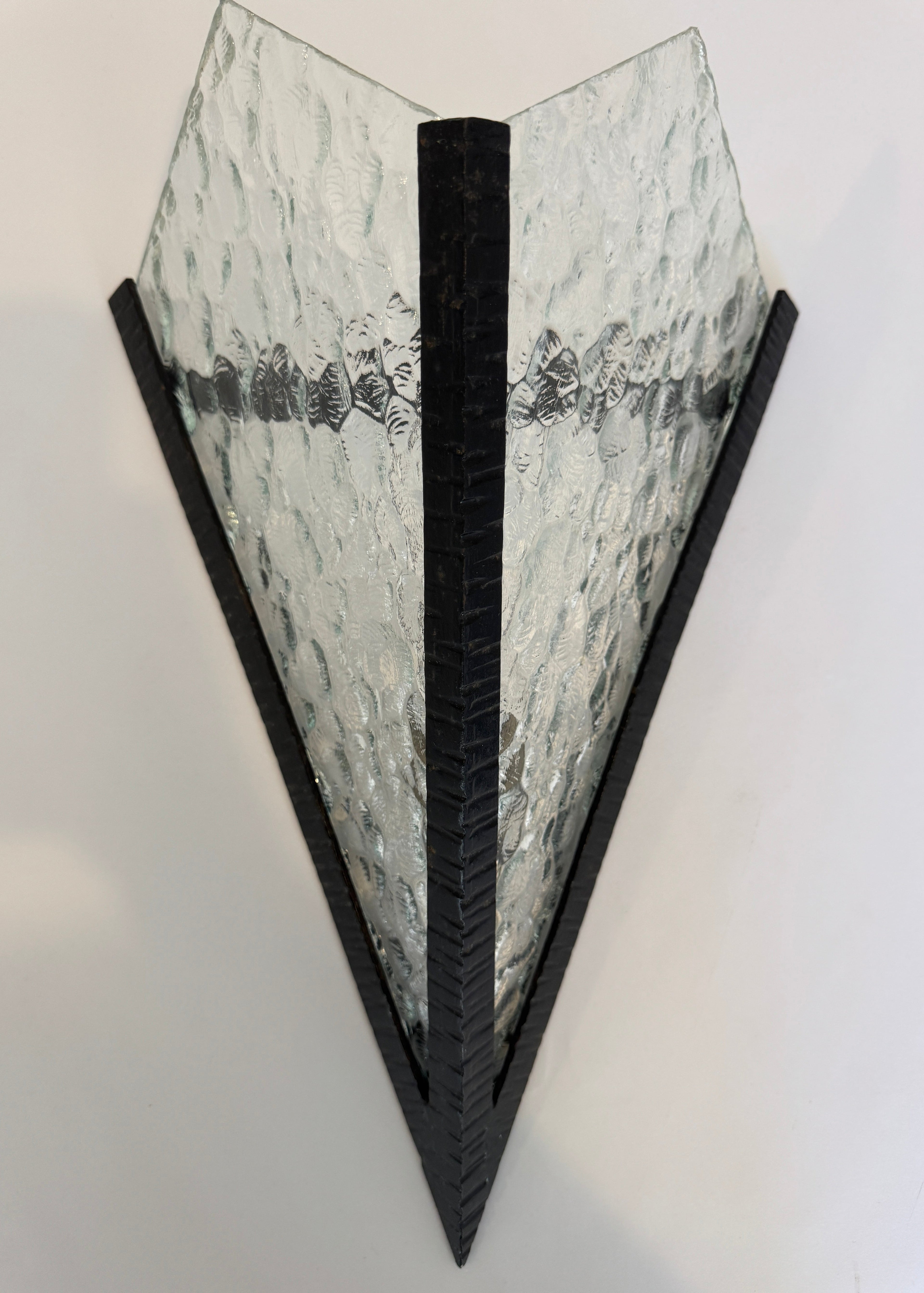 Triangular wall sconce with textured glass shade on a white background