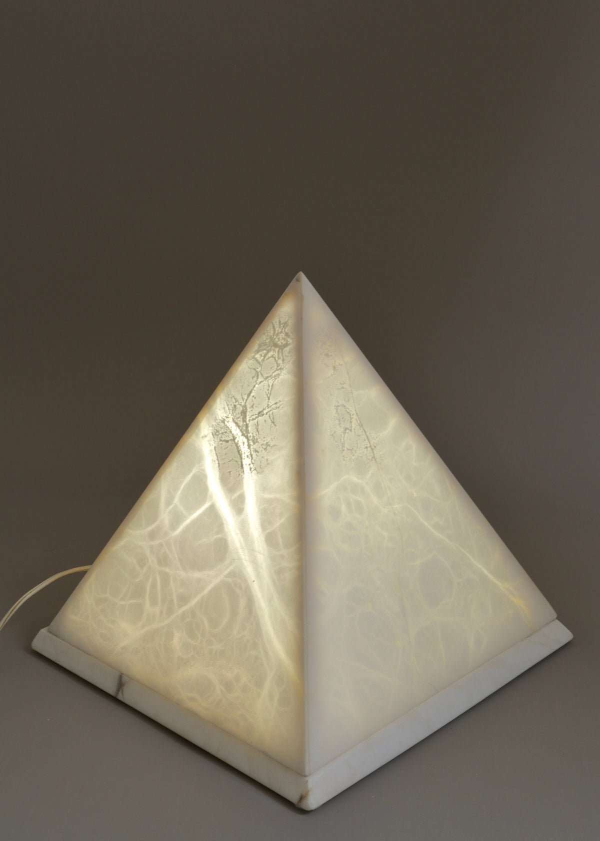 Illuminated vintage marble pyramid table lamp showing natural veining through the translucent stone.