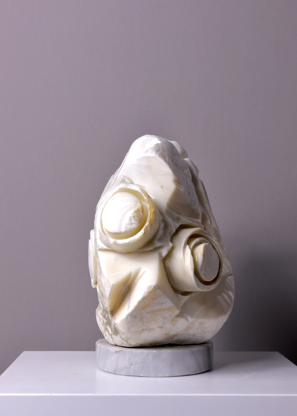 White marble sculpture table lamp on a gray surface with a gray background