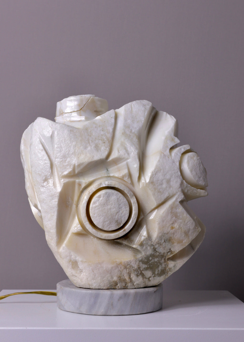White marble sculpture table lamp on a gray surface with a gray background