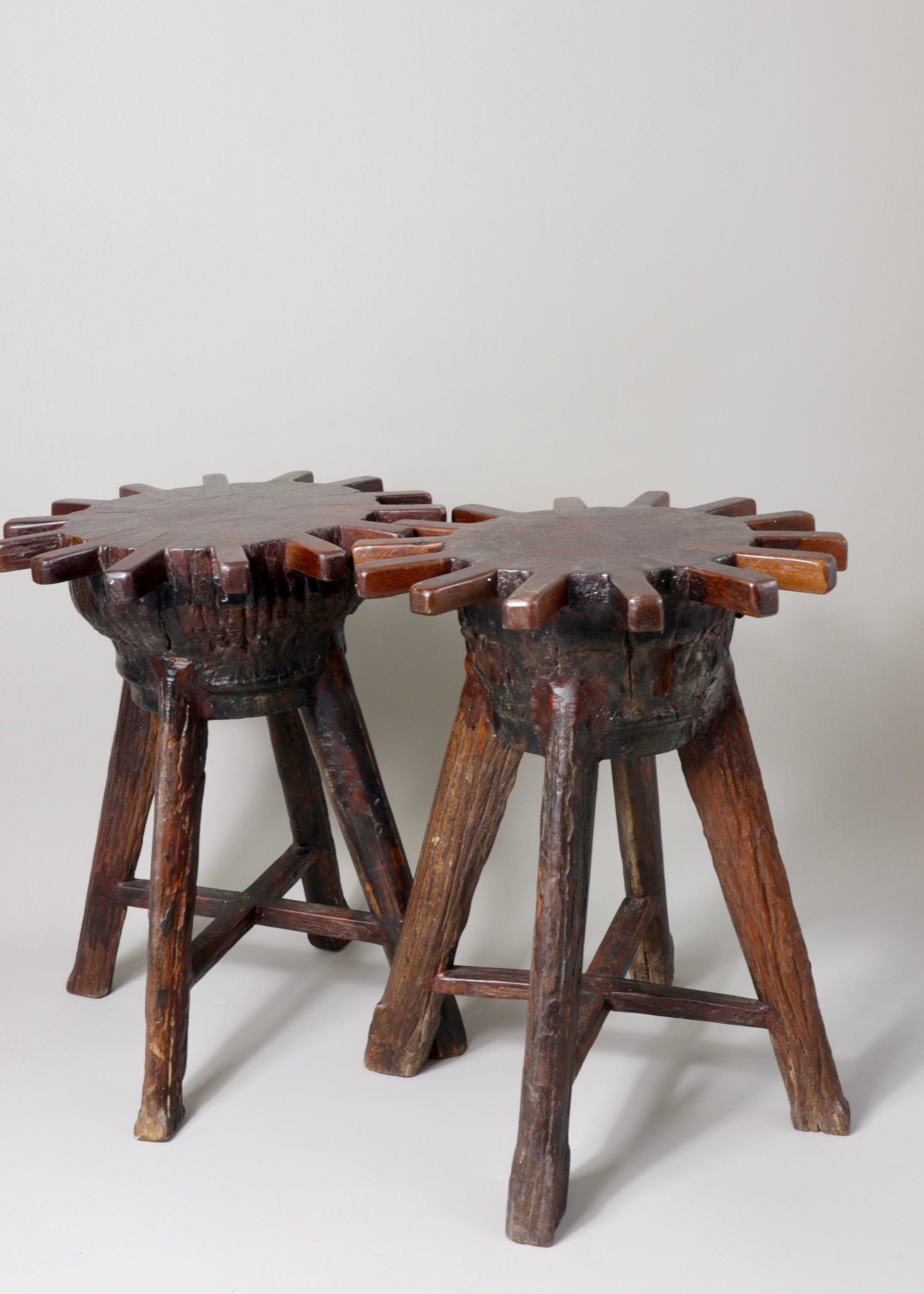 a pair of hand carved brutalist primitive french wooden stools with sunburst tops and patina