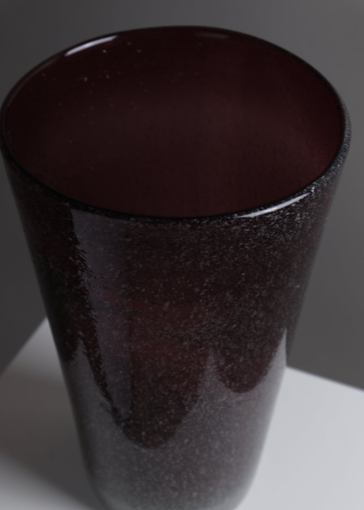 Detail of the vase’s smoky grey base transitioning into deep burgundy pulegoso glass.