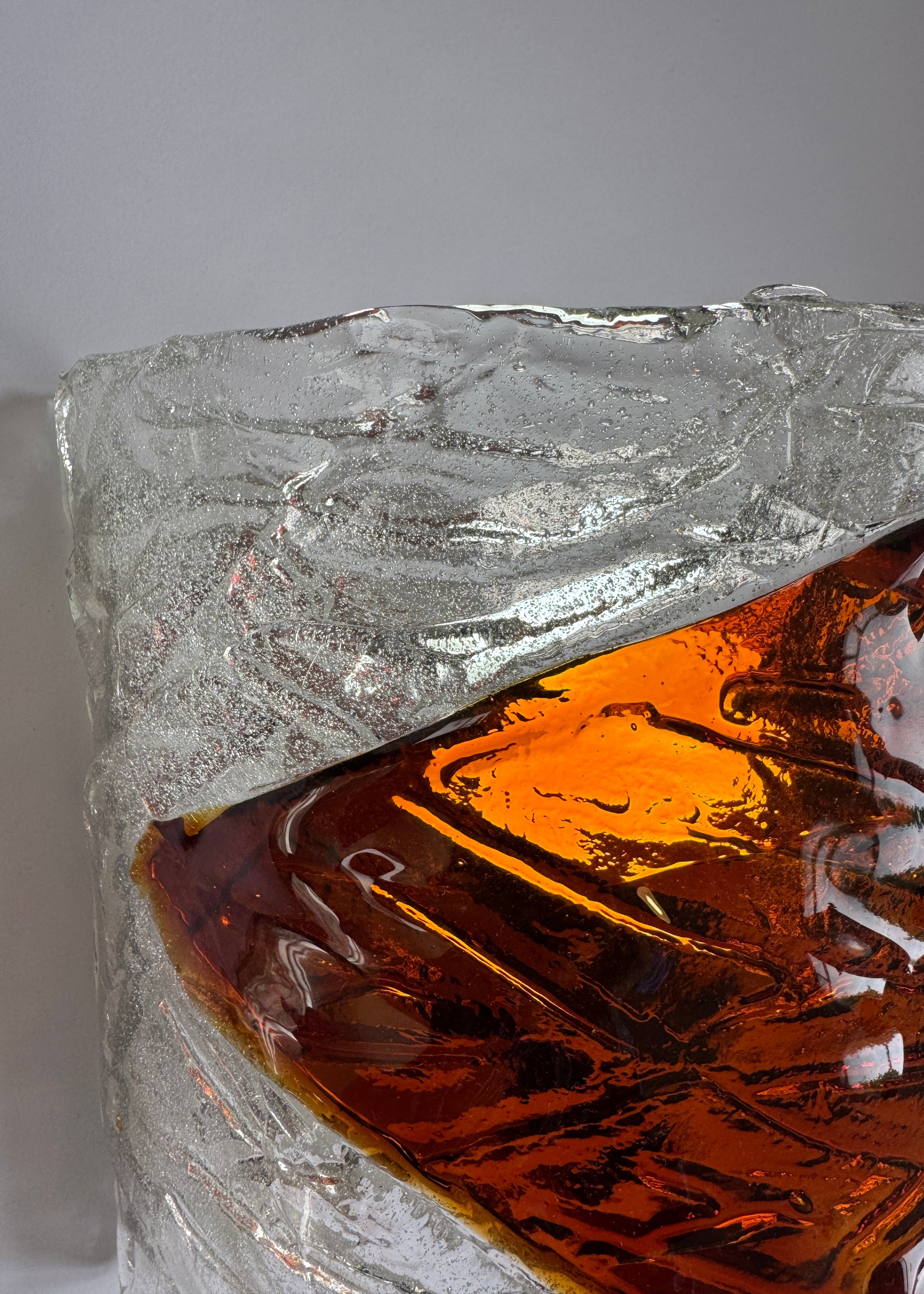 Close-up of a crystal with amber-colored murano sconce on a gray background