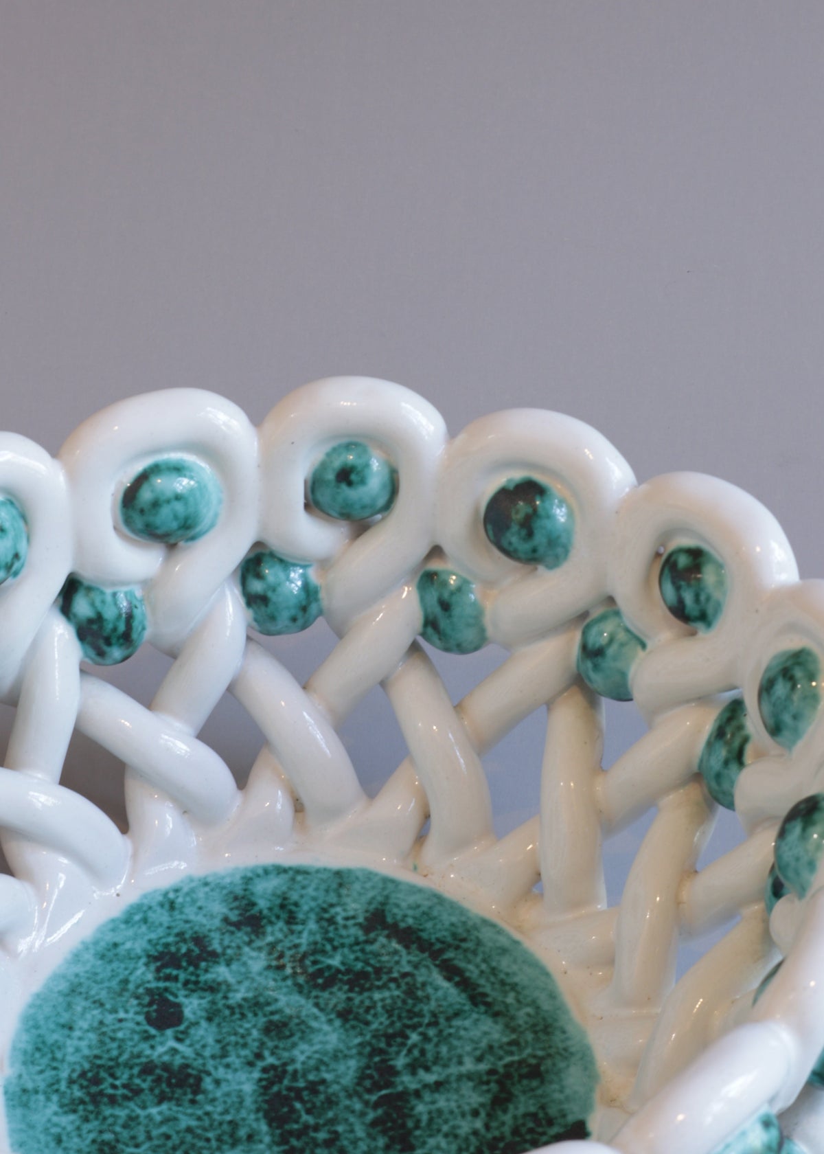Side view of the Sainte Radegonde vase showing its rounded green-speckled body, raised foot and undulating white ceramic rim.