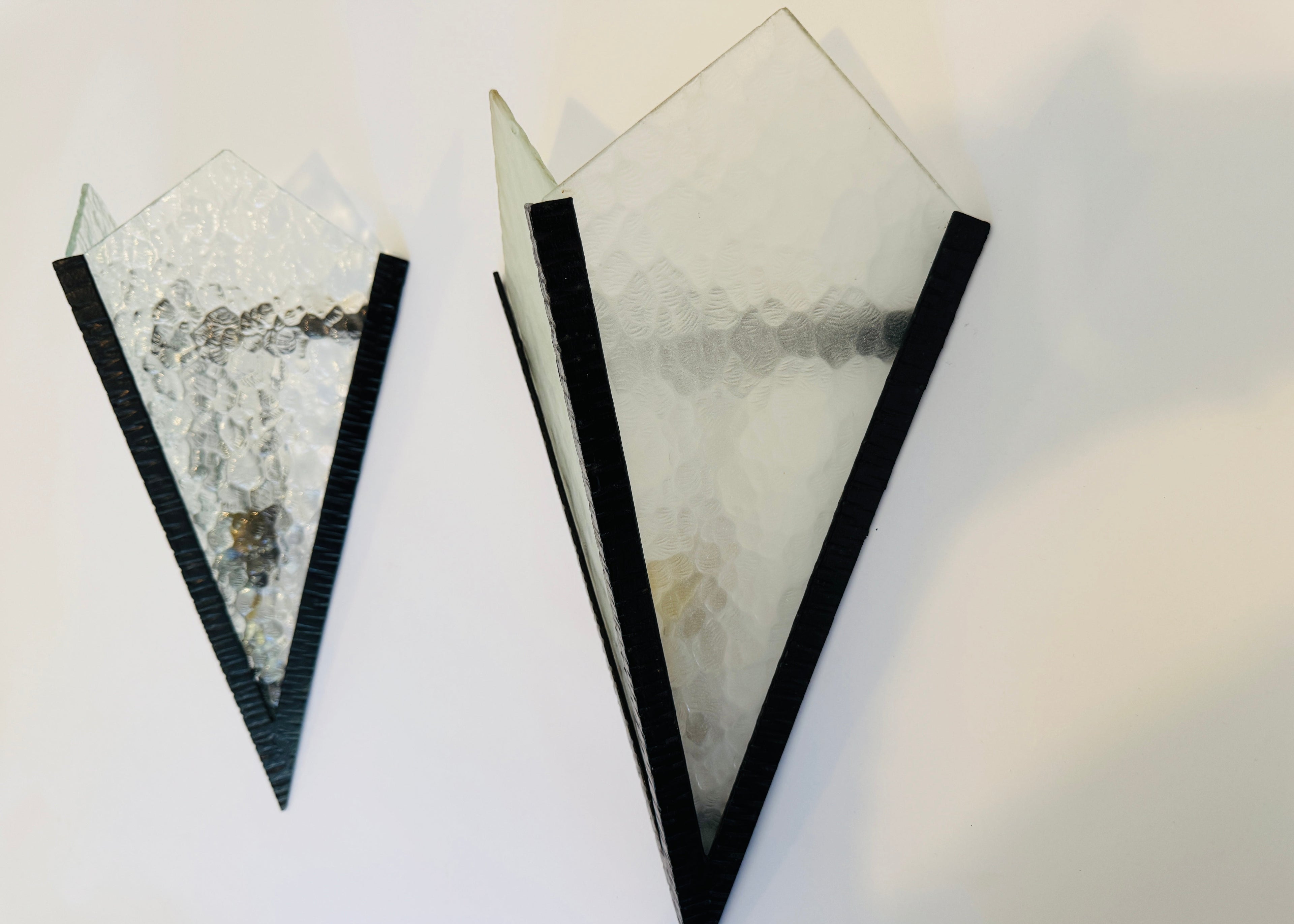 Two geometrically shaped sconces with black borders on a white background