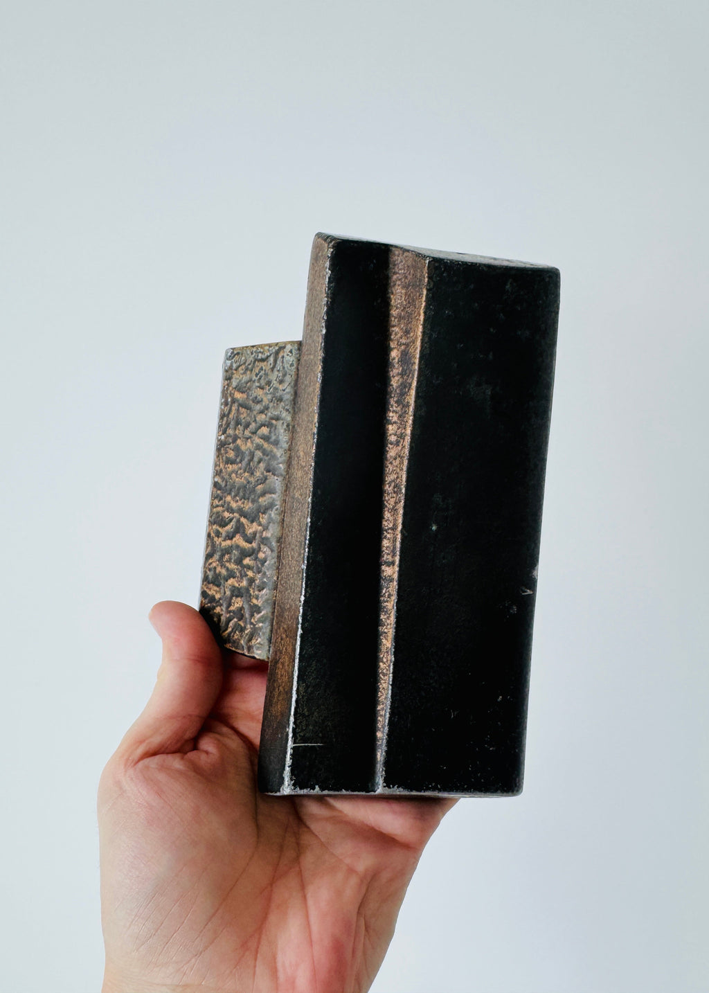 Vintage Brutalist sculptural door handle in dark patinated metal with angular folded grip and textured rectangular mounting plate.