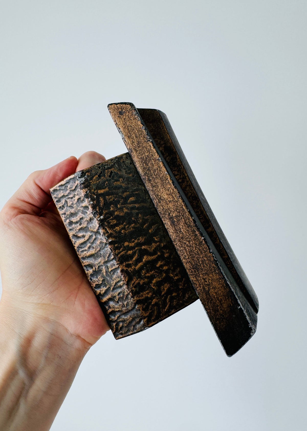 Vintage Brutalist sculptural door handle in dark patinated metal with angular folded grip and textured rectangular mounting plate.