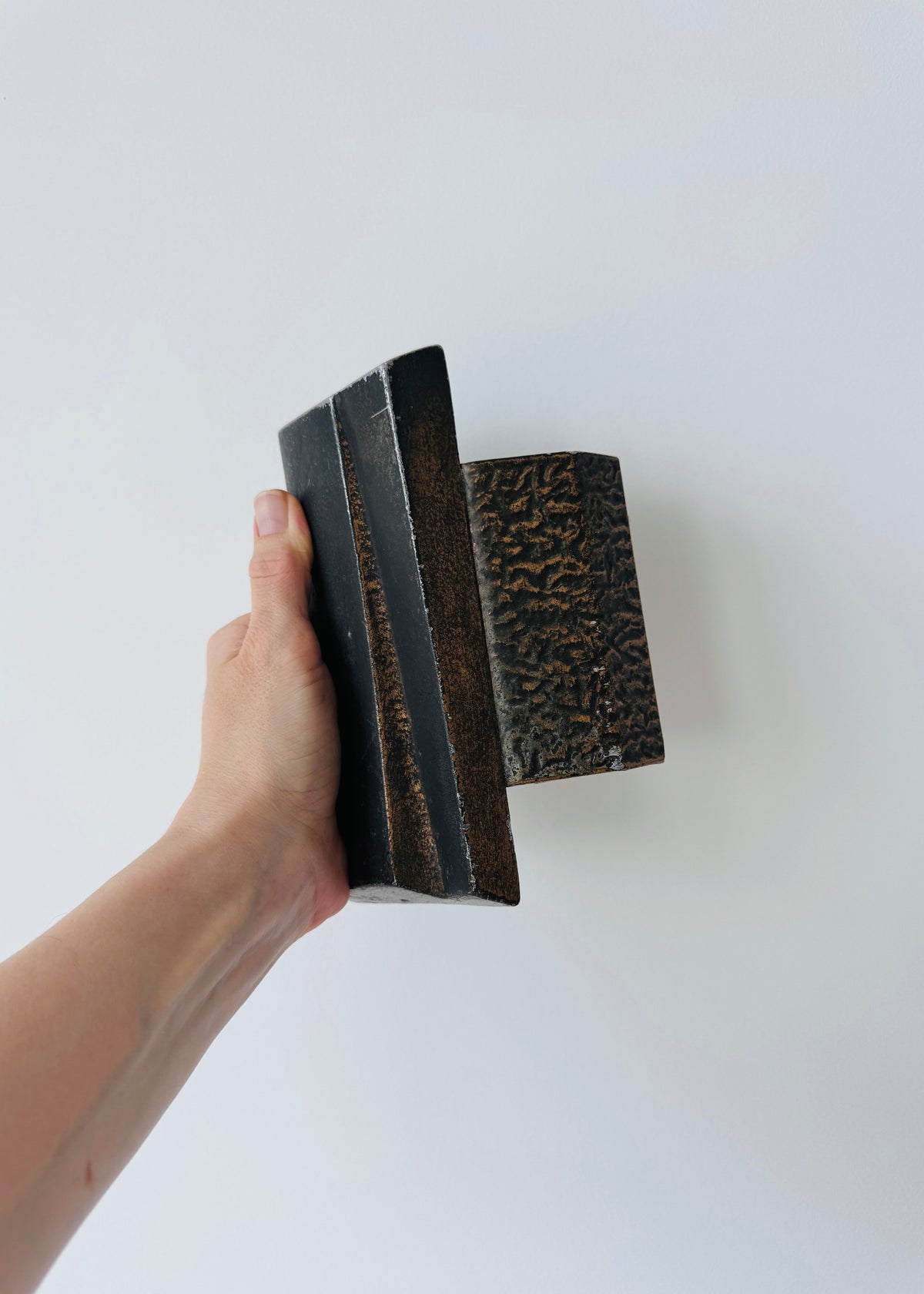 Vintage Brutalist sculptural door handle in dark patinated metal with angular folded grip and textured rectangular mounting plate.