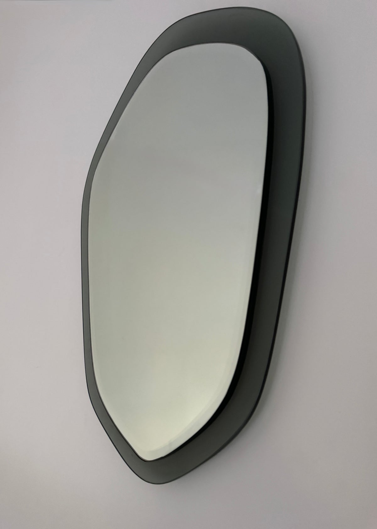 Detail of the smoked acrylic surround and reflective glass on a 1970s Italian shield mirror.