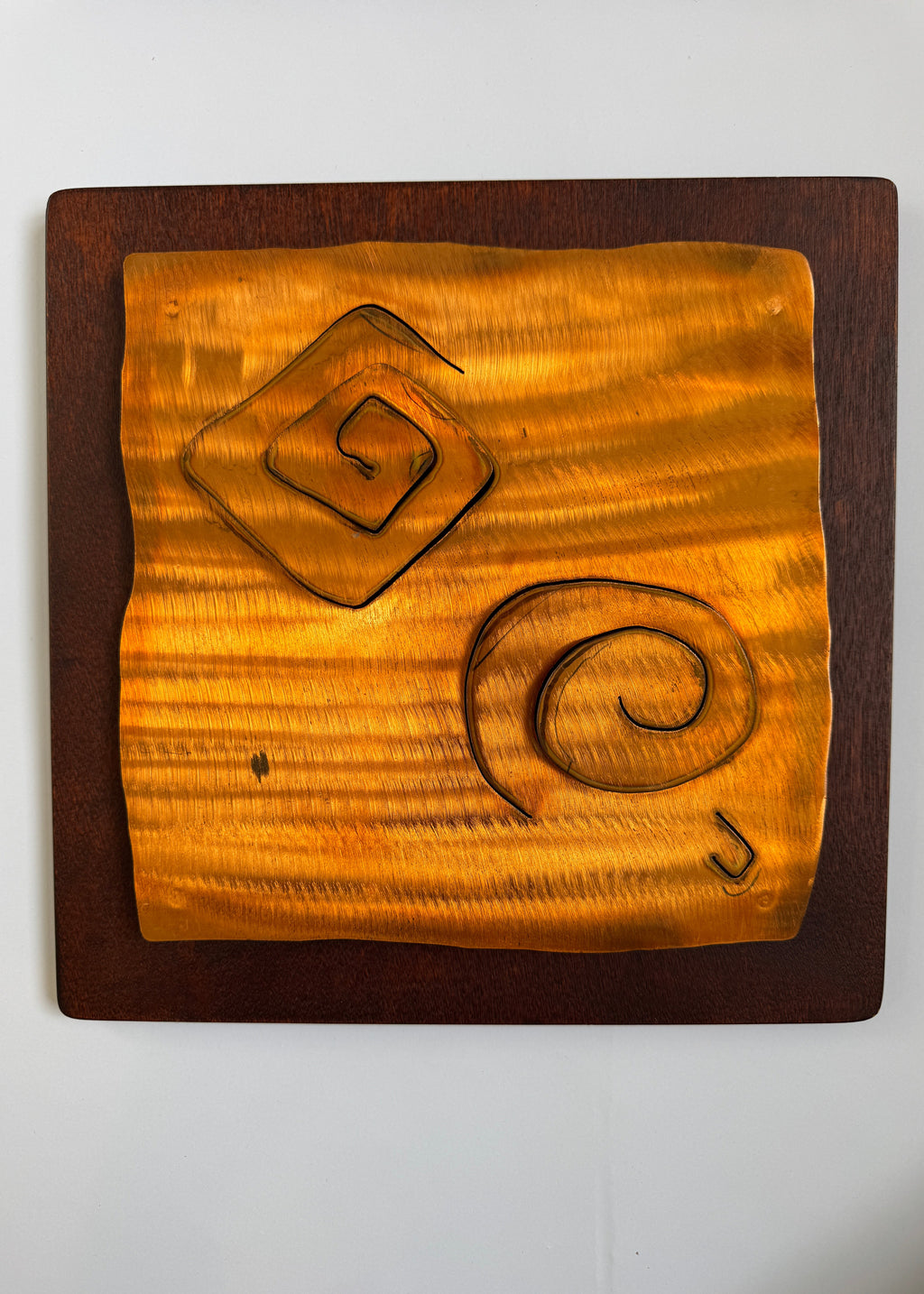 Wooden plaque with geometric carvings on a white background